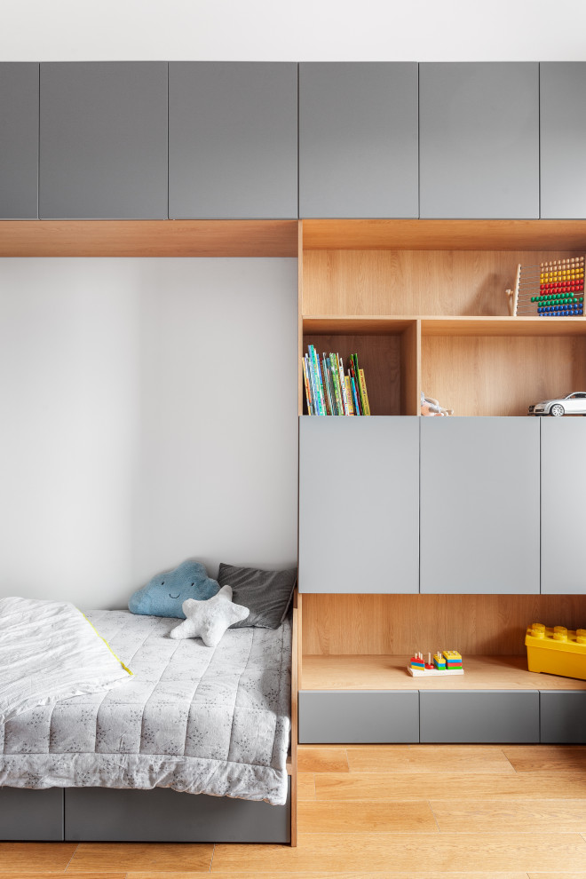 Photo of a contemporary gender-neutral kids' bedroom for kids 4-10 years old in Other with white walls, medium hardwood floors and brown floor.