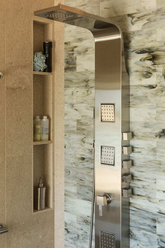 Contemporary master bathroom in Hawaii with furniture-like cabinets, medium wood cabinets, an undermount tub, a curbless shower, a bidet, blue tile, limestone, beige walls, limestone floors, an undermount sink, granite benchtops, beige floor, a hinged shower door and blue benchtops.
