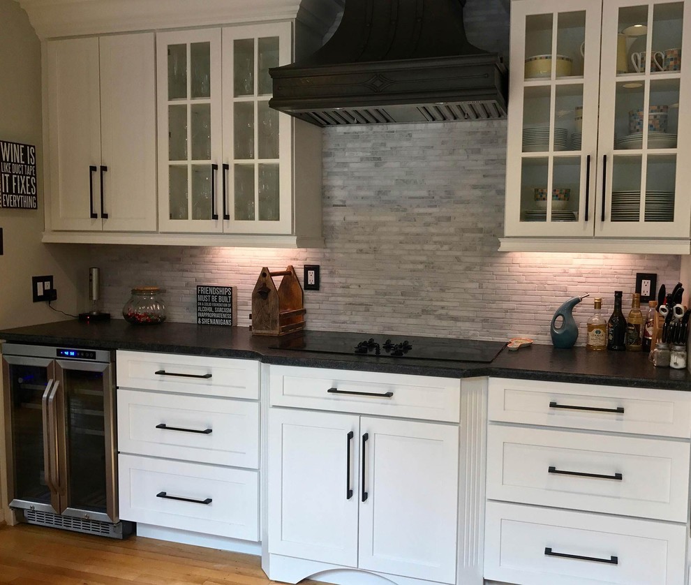 Mid-sized country l-shaped separate kitchen in Philadelphia with a farmhouse sink, shaker cabinets, white cabinets, quartz benchtops, grey splashback, marble splashback, stainless steel appliances, medium hardwood floors, a peninsula and brown floor.