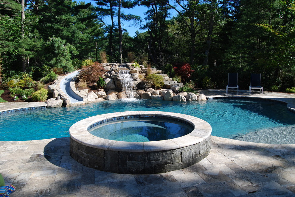 This is an example of a mid-sized country backyard kidney-shaped natural pool in Boston with a water slide and natural stone pavers.