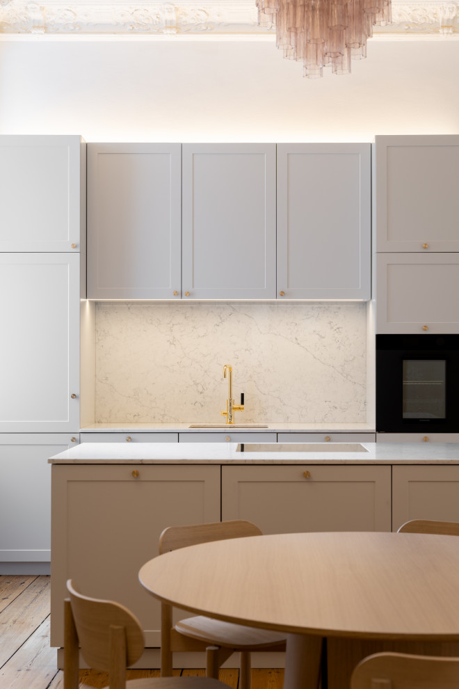 Esempio di una cucina minimalista chiusa e di medie dimensioni con lavello sottopiano, ante con bugna sagomata, ante grigie, top in superficie solida, paraspruzzi grigio, paraspruzzi in marmo, elettrodomestici neri e top bianco