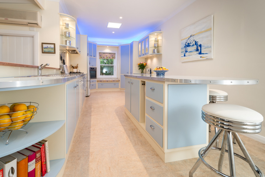 This is an example of a large eclectic u-shaped separate kitchen in Adelaide with a double-bowl sink, raised-panel cabinets, blue cabinets, laminate benchtops, white splashback, glass sheet splashback, black appliances, linoleum floors and with island.