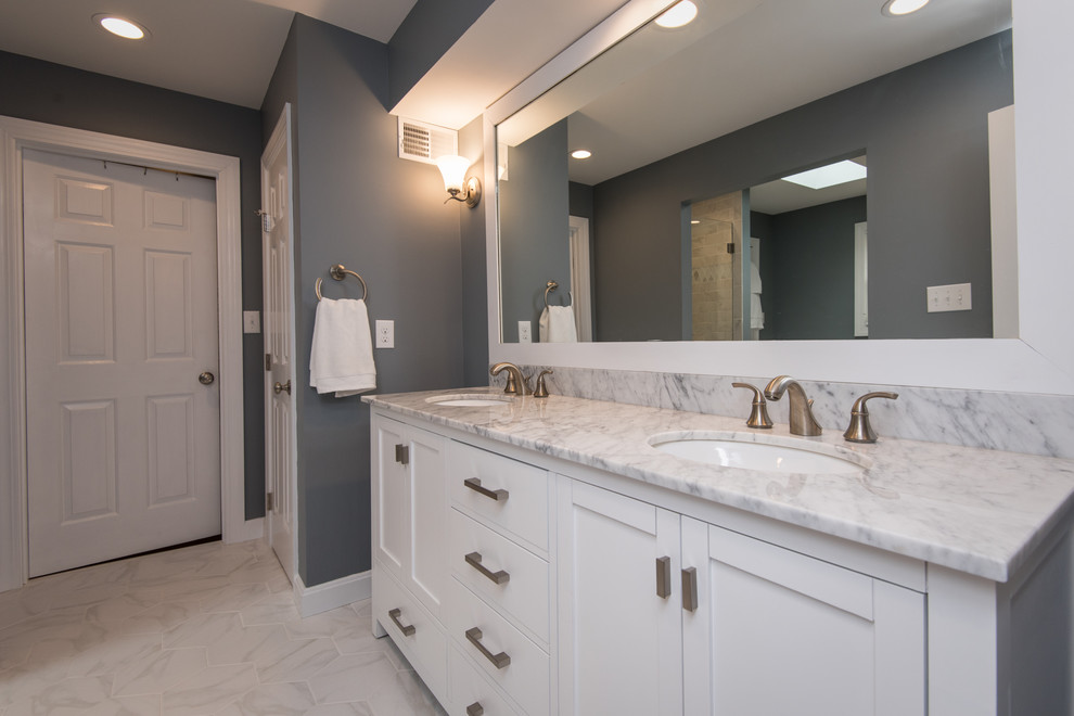 This is an example of a large transitional master bathroom in Louisville with shaker cabinets, white cabinets, a freestanding tub, an alcove shower, white tile, subway tile, grey walls, marble floors, an undermount sink, marble benchtops, white floor and a hinged shower door.