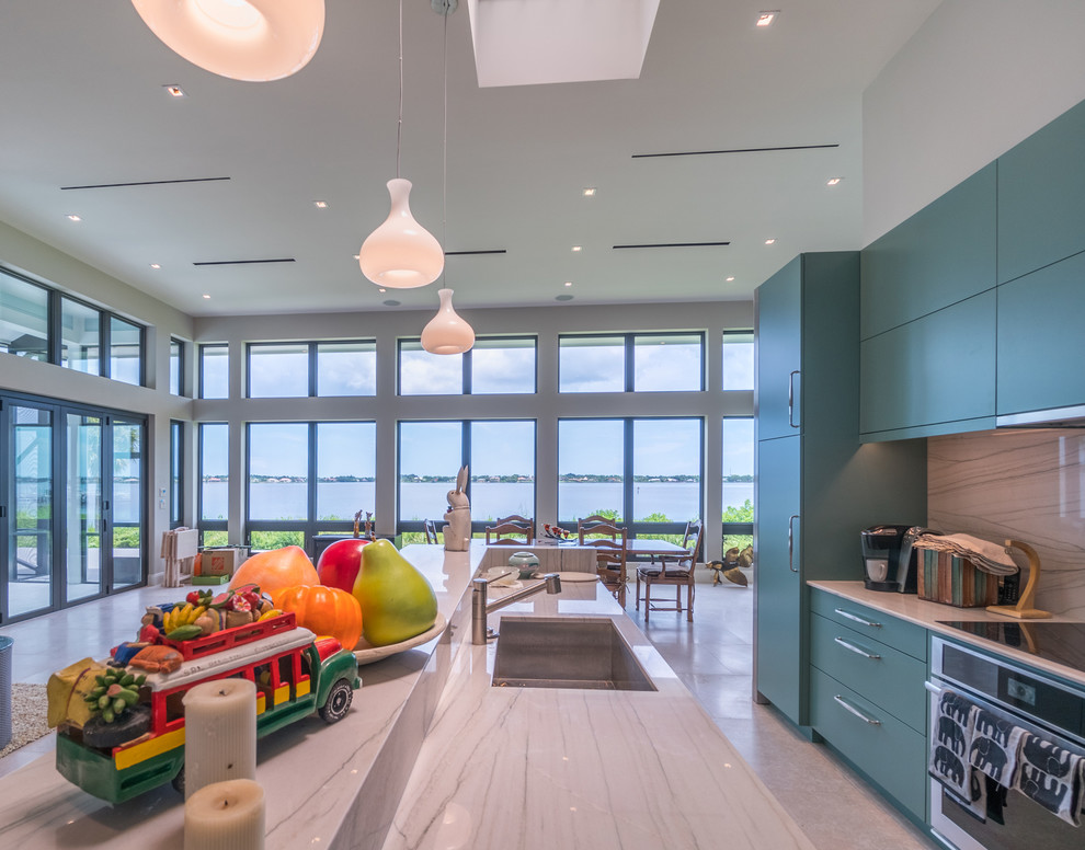 This is an example of a modern l-shaped open plan kitchen in Miami with an undermount sink, flat-panel cabinets, green cabinets, onyx benchtops, grey splashback, stone slab splashback, stainless steel appliances, limestone floors and with island.