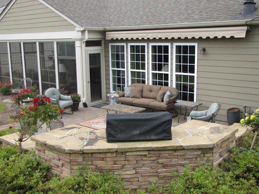 Inspiration for a mid-sized traditional backyard patio in Orange County with an outdoor kitchen, natural stone pavers and an awning.