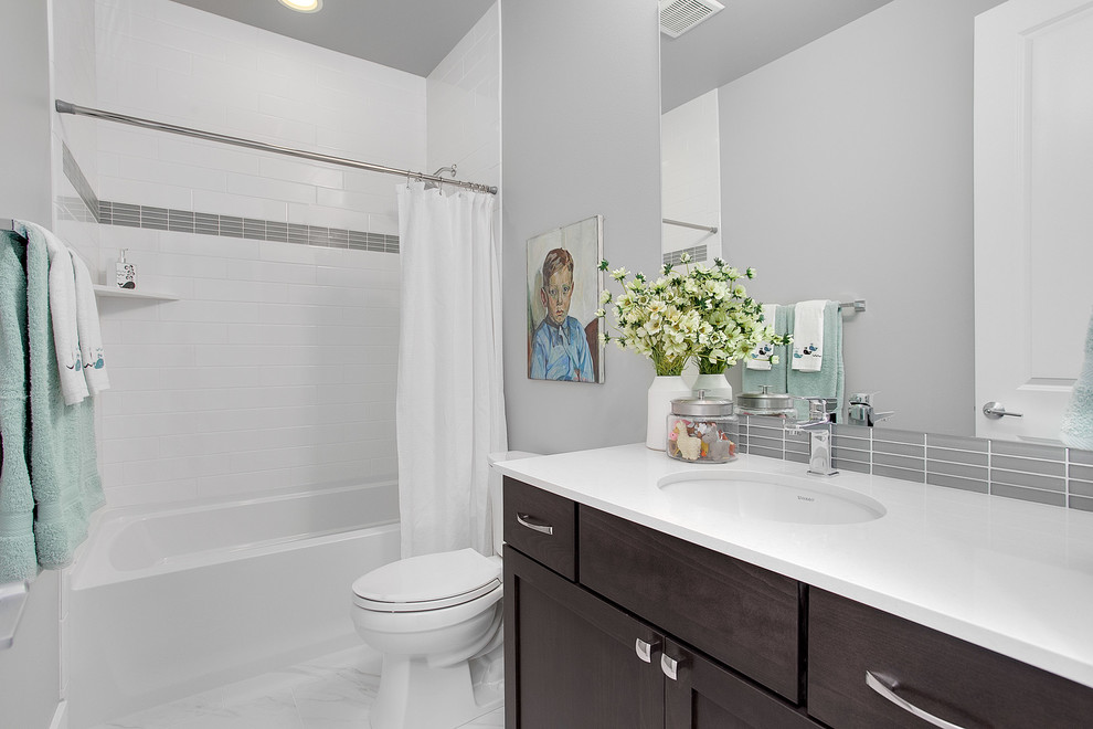 Inspiration for a large transitional bathroom in Seattle with shaker cabinets, dark wood cabinets, a shower/bathtub combo, a two-piece toilet, gray tile, grey walls, an undermount sink and engineered quartz benchtops.