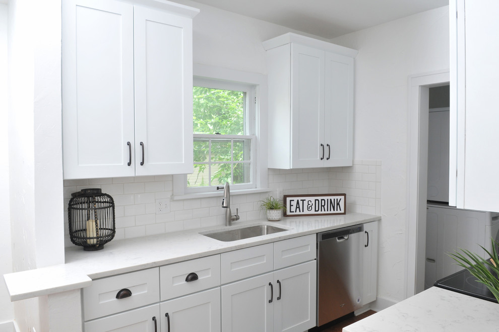 This is an example of a small scandinavian galley separate kitchen in Oklahoma City with an undermount sink, shaker cabinets, white cabinets, quartzite benchtops, white splashback, ceramic splashback, stainless steel appliances, medium hardwood floors, with island, brown floor and white benchtop.