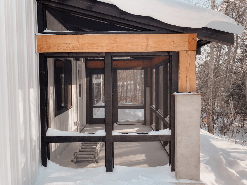 Cette photo montre un porche d'entrée de maison arrière nature de taille moyenne avec des colonnes, une dalle de béton, une extension de toiture et un garde-corps en bois.