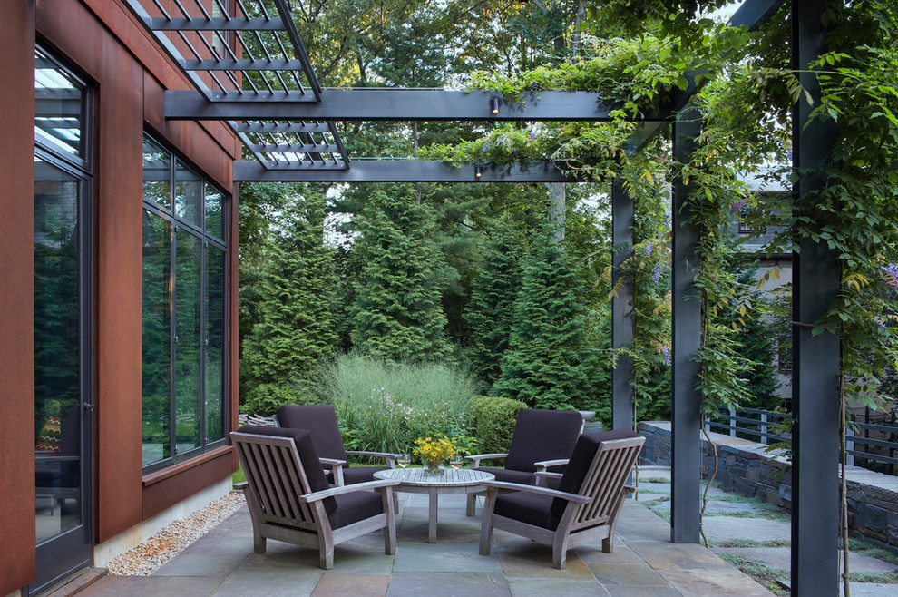 This is an example of a contemporary backyard patio in Boston with a pergola and natural stone pavers.