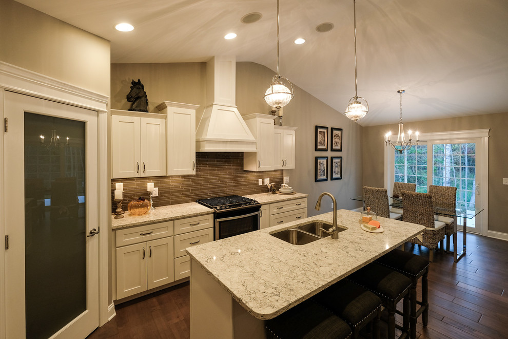 Example of a mid-sized transitional l-shaped dark wood floor and brown floor eat-in kitchen design with an undermount sink, recessed-panel cabinets, white cabinets, quartz countertops, brown backsplash, stainless steel appliances, an island and white countertops