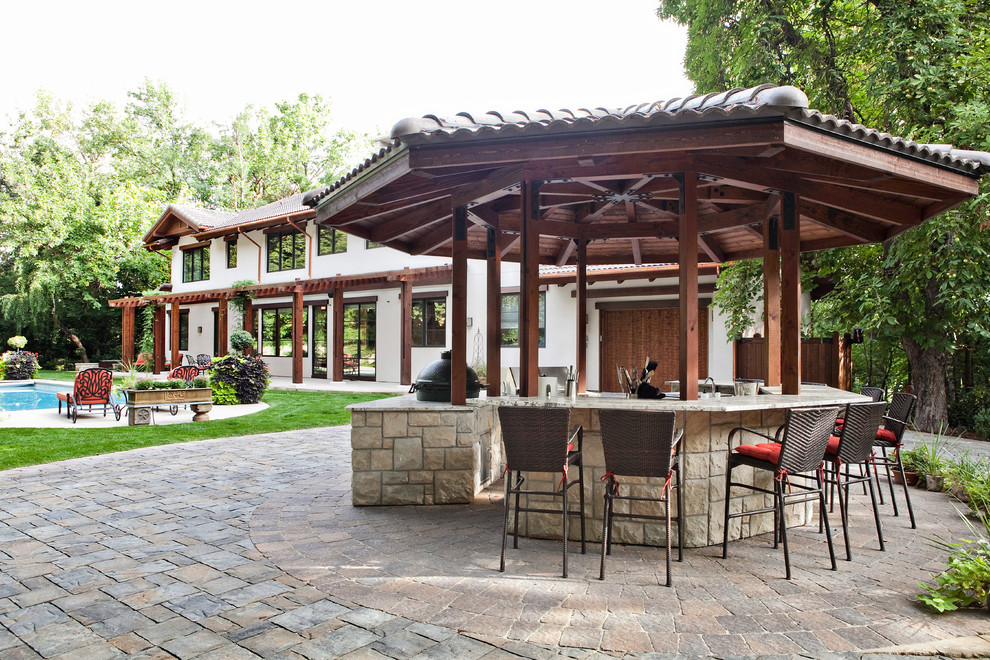 This is an example of a mid-sized mediterranean backyard patio in Boise with an outdoor kitchen, natural stone pavers and a gazebo/cabana.