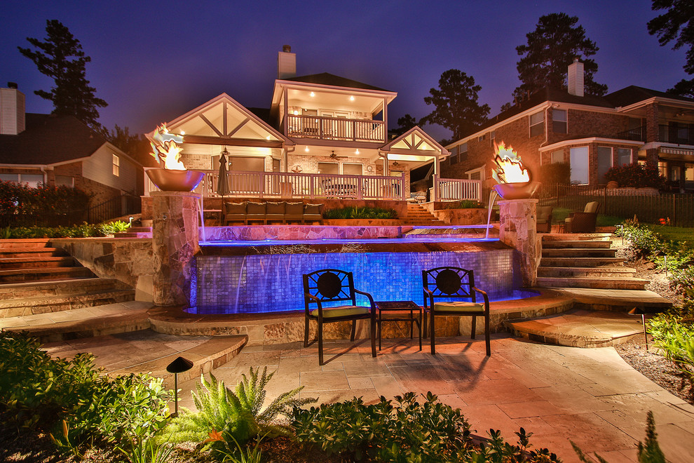 Inspiration for an expansive eclectic backyard custom-shaped infinity pool in Houston with a water feature and tile.