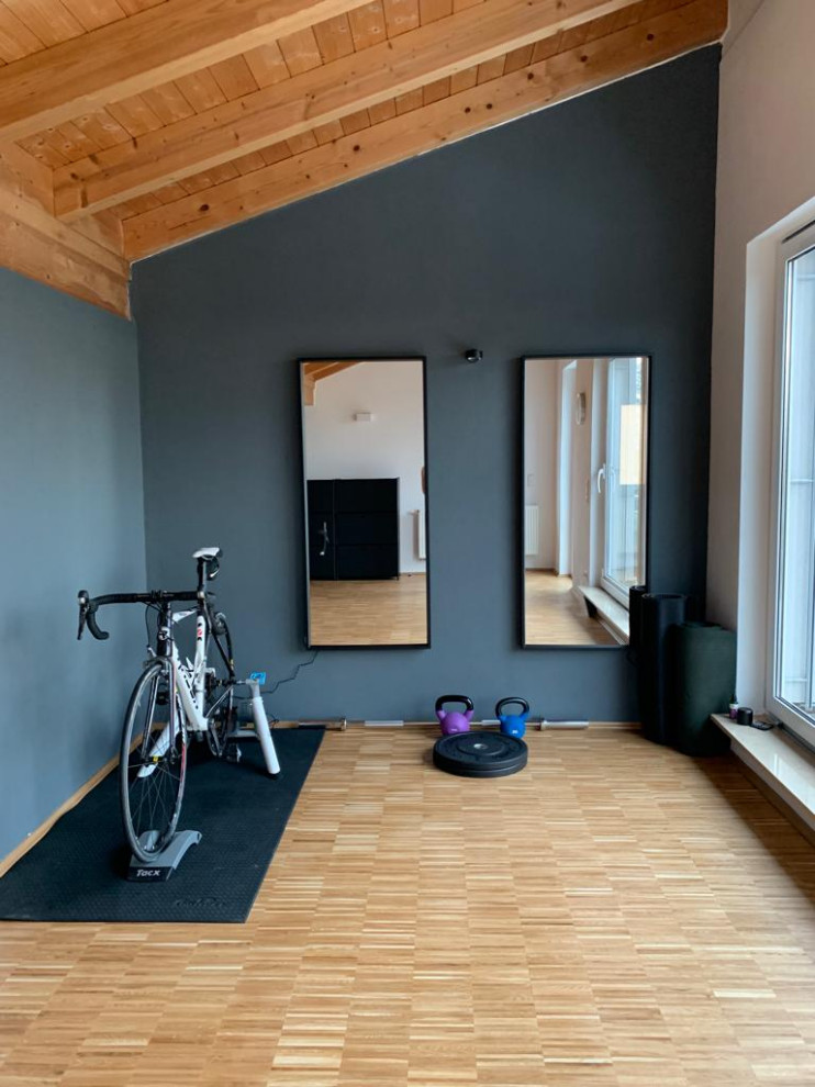 This is an example of a small scandinavian multi-use home gym in Nuremberg with black walls, medium hardwood flooring, brown floors and a wood ceiling.