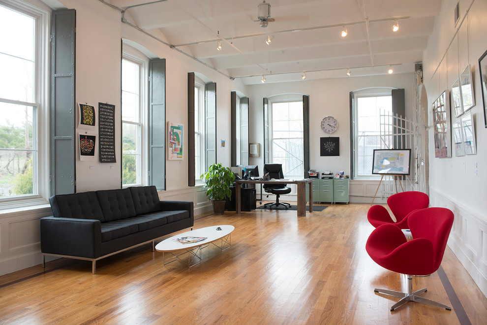 Photo of an industrial living room in New York with white walls and medium hardwood floors.