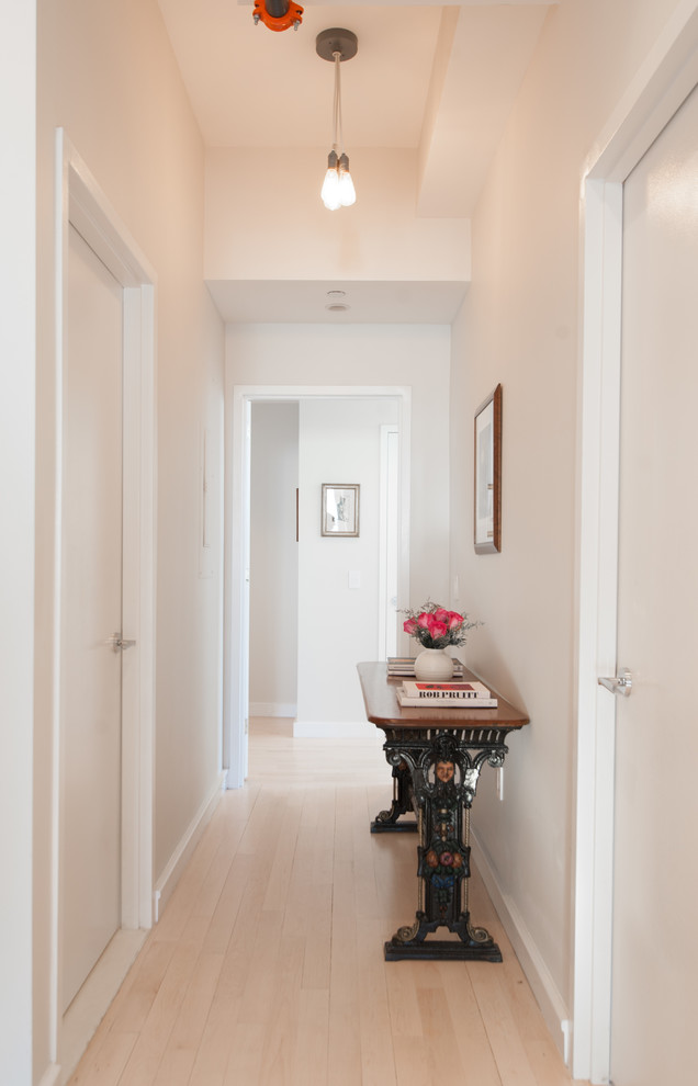 Inspiration for a small contemporary hallway in New York with light hardwood floors and white walls.