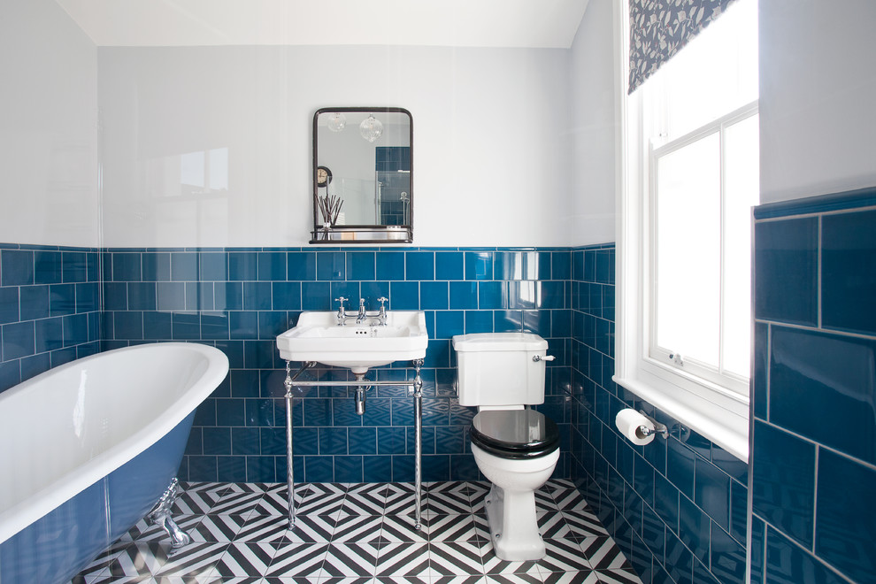 Small traditional bathroom in Sussex with a corner shower, a one-piece toilet, blue tile, ceramic tile, white walls, ceramic floors, a pedestal sink, multi-coloured floor and a hinged shower door.