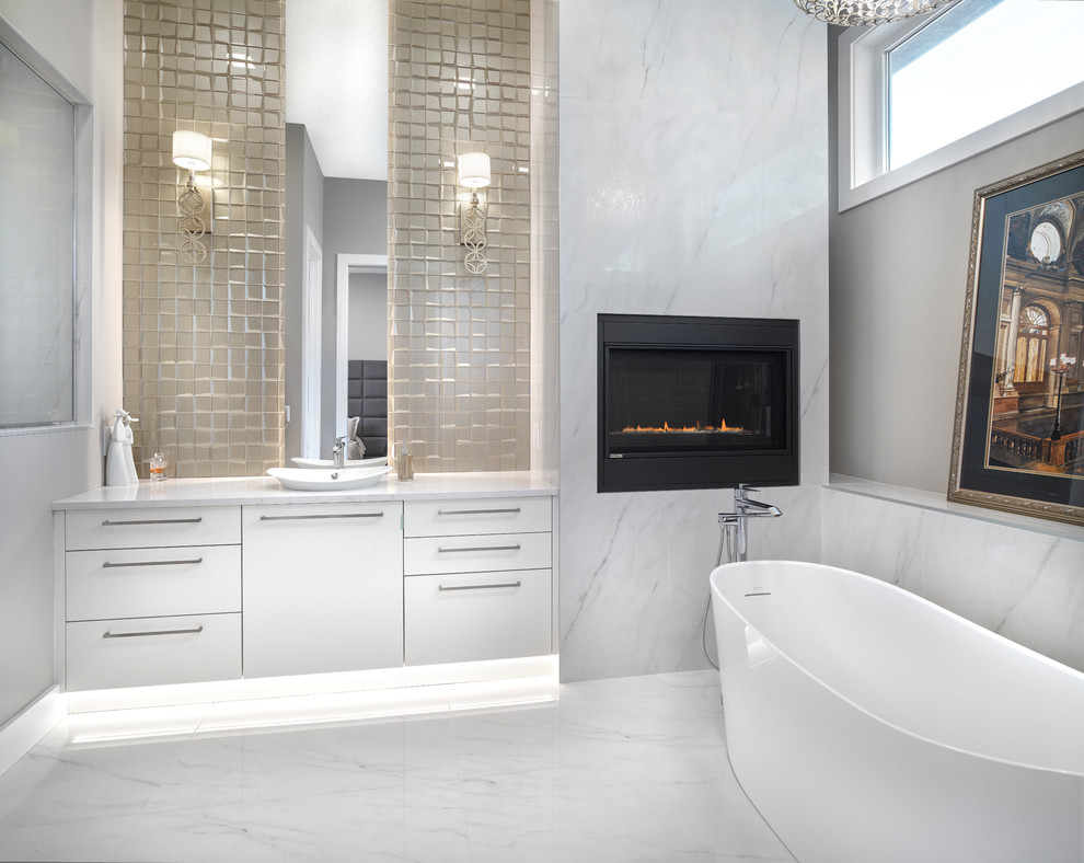 Photo of a large modern master bathroom in Edmonton with flat-panel cabinets, white cabinets, a freestanding tub, a curbless shower, beige tile, glass tile, porcelain floors, a drop-in sink, engineered quartz benchtops, white floor and white benchtops.