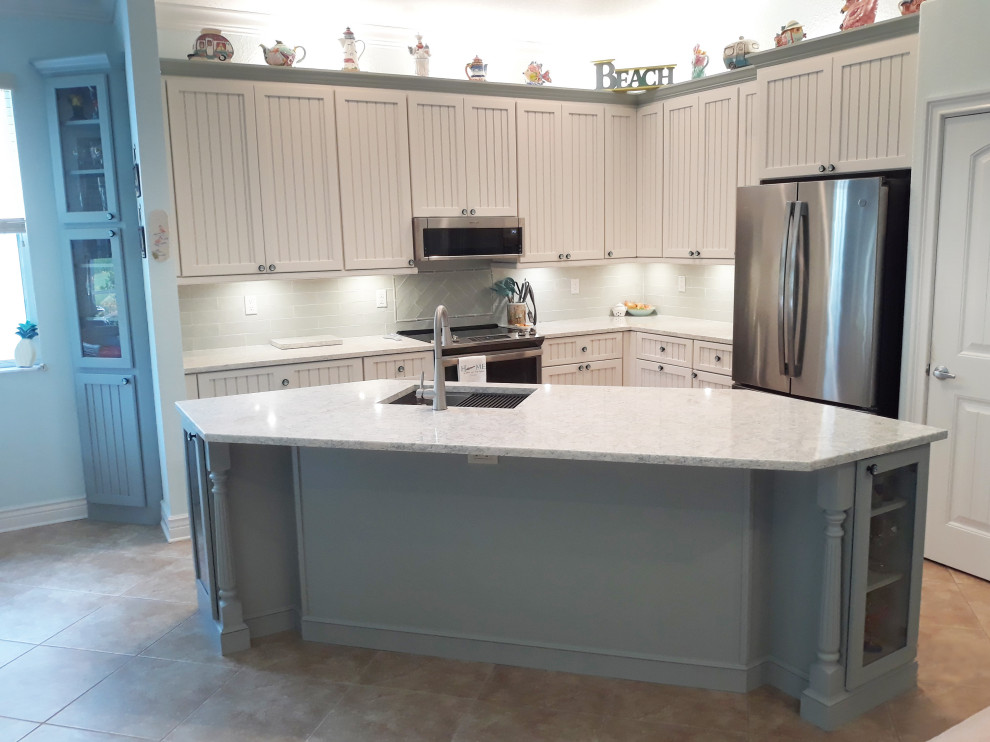 Example of a transitional eat-in kitchen design with a single-bowl sink, shaker cabinets, white cabinets, quartz countertops, stainless steel appliances, an island and multicolored countertops