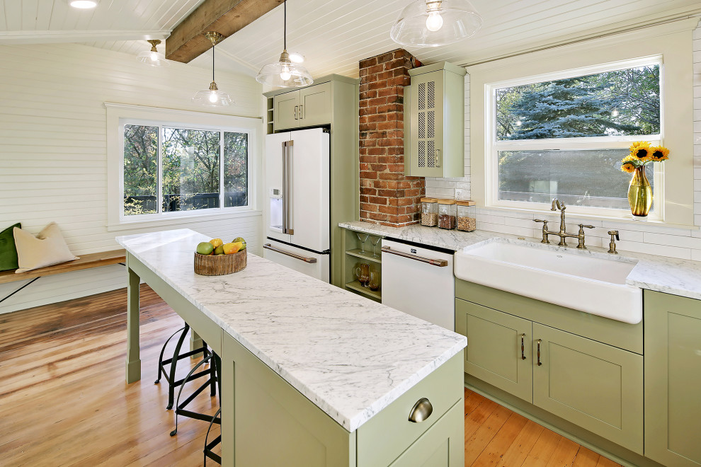Large arts and crafts separate kitchen in Seattle with a farmhouse sink, green cabinets, white splashback, white appliances, medium hardwood floors, with island, brown floor and multi-coloured benchtop.