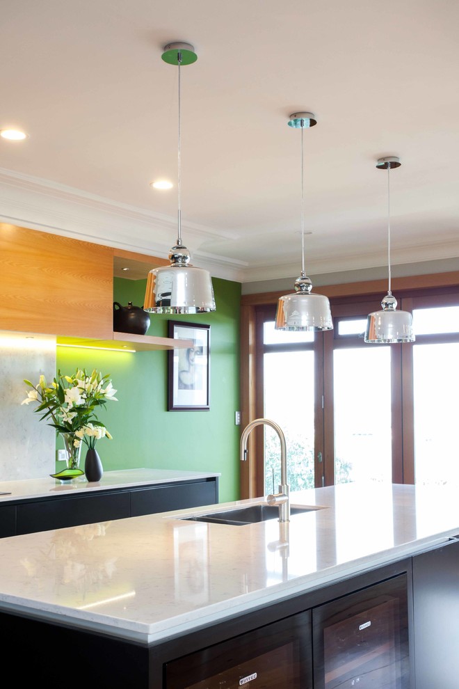 Inspiration for a mid-sized modern galley open plan kitchen in Auckland with an undermount sink, recessed-panel cabinets, black cabinets, quartz benchtops, white splashback, stone slab splashback, stainless steel appliances, medium hardwood floors and with island.