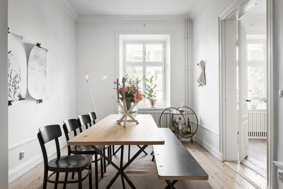Photo of a mid-sized scandinavian separate dining room in Stockholm with white walls and light hardwood floors.