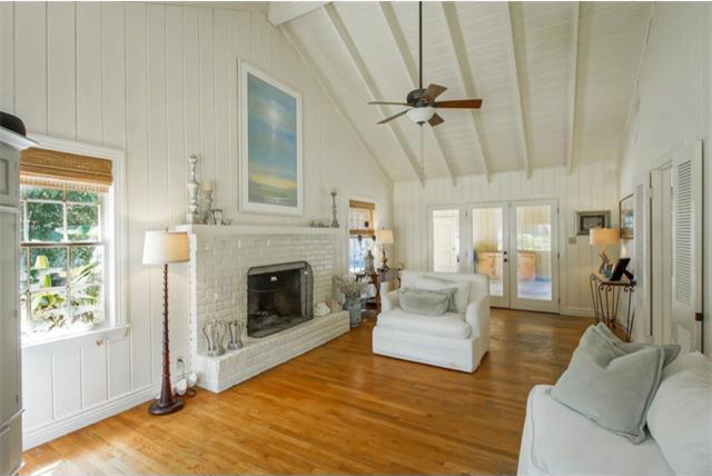 Mid-sized country formal enclosed living room in New Orleans with white walls, medium hardwood floors, a standard fireplace, a brick fireplace surround, no tv and white floor.