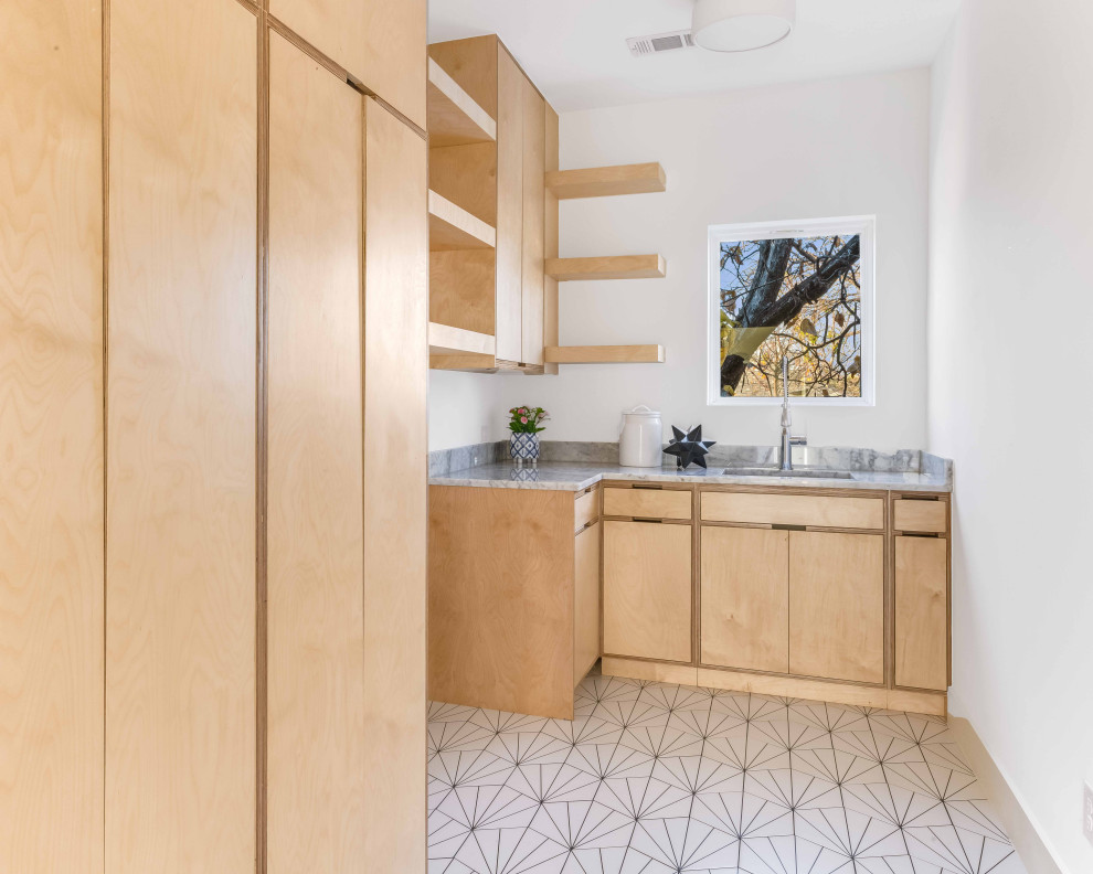 Large beach style l-shaped dedicated laundry room in Dallas with an undermount sink, flat-panel cabinets, brown cabinets, marble benchtops, grey splashback, marble splashback, white walls, porcelain floors, a side-by-side washer and dryer, white floor and grey benchtop.