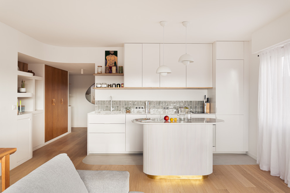 Idéer för ett modernt vit kök, med en undermonterad diskho, släta luckor, vita skåp, stänkskydd med metallisk yta, stänkskydd i metallkakel, integrerade vitvaror, en köksö och grått golv