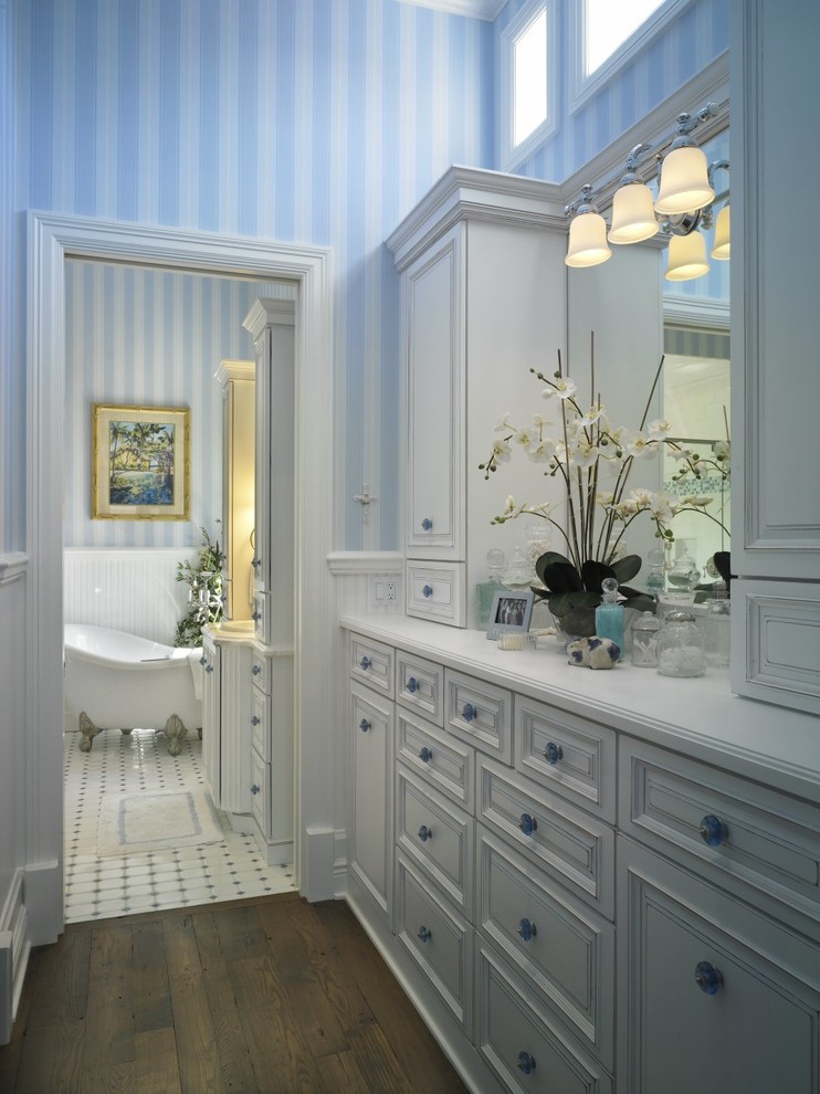 Inspiration for a mid-sized beach style kids bathroom in Wichita with a drop-in sink, raised-panel cabinets, white cabinets, solid surface benchtops, a claw-foot tub, white tile, ceramic tile, blue walls and medium hardwood floors.