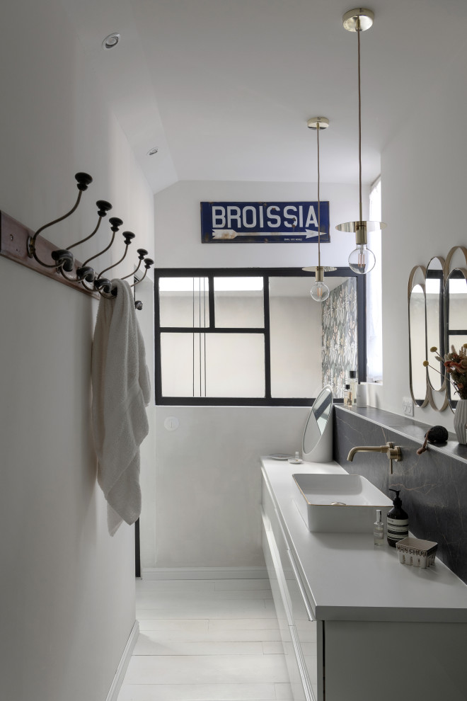 This is an example of a mid-sized mediterranean 3/4 bathroom in Saint-Etienne with flat-panel cabinets, white cabinets, a curbless shower, a wall-mount toilet, black tile, marble, white walls, painted wood floors, a trough sink, white floor, an open shower, a single vanity and a floating vanity.