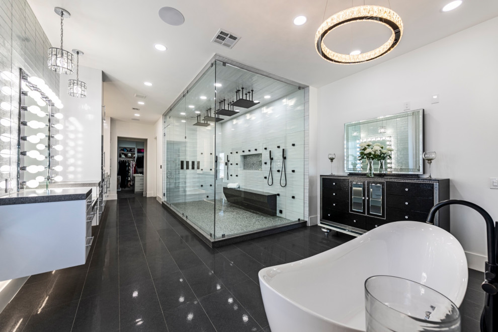 Стильный дизайн: огромная главная ванная комната в современном стиле с плоскими фасадами, белыми фасадами, отдельно стоящей ванной, двойным душем, унитазом-моноблоком, серой плиткой, стеклянной плиткой, белыми стенами, полом из керамической плитки, накладной раковиной, столешницей из гранита, серым полом, душем с распашными дверями, серой столешницей, тумбой под две раковины и подвесной тумбой - последний тренд