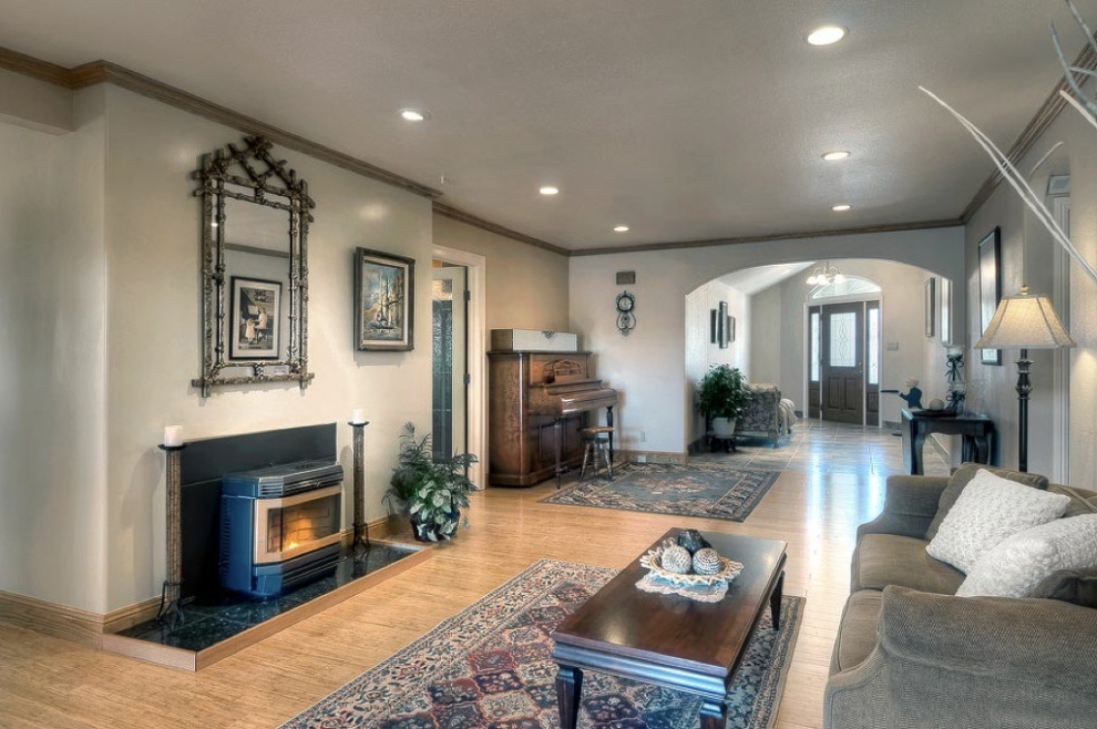This is an example of a traditional open concept living room in Salt Lake City with beige walls, bamboo floors, a wood stove, a stone fireplace surround and brown floor.