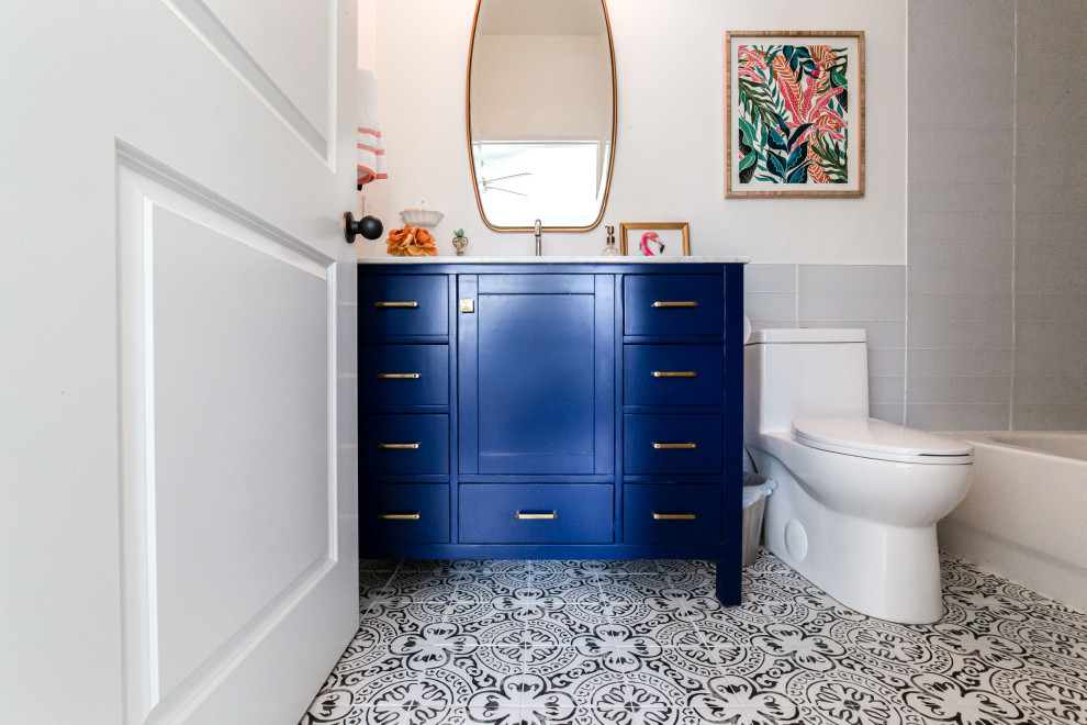 Inspiration for a mid-sized contemporary kids bathroom in Atlanta with shaker cabinets, blue cabinets, a freestanding tub, a shower/bathtub combo, a one-piece toilet, black and white tile, cement tile, white walls, cement tiles, an undermount sink, marble benchtops, multi-coloured floor, a shower curtain, white benchtops, a niche, a single vanity and a freestanding vanity.