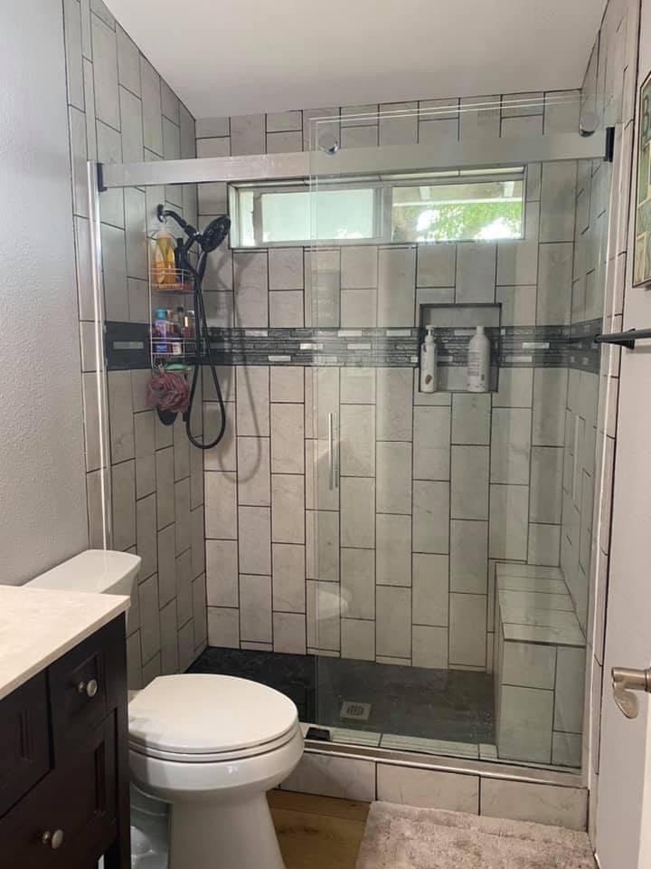 Small country 3/4 bathroom with white cabinets, an open shower, a one-piece toilet, grey walls, vinyl floors, a console sink, marble benchtops, brown floor, white benchtops and a single vanity.