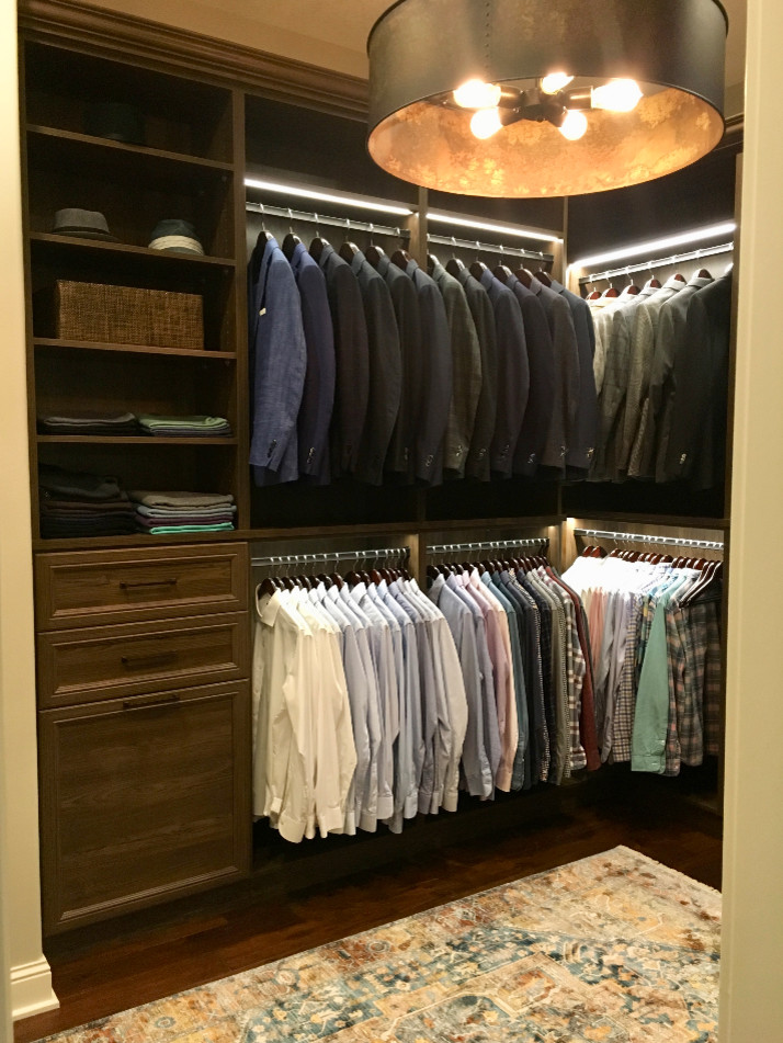 Photo of a large traditional men's walk-in wardrobe in Minneapolis with raised-panel cabinets, dark wood cabinets, dark hardwood floors and brown floor.