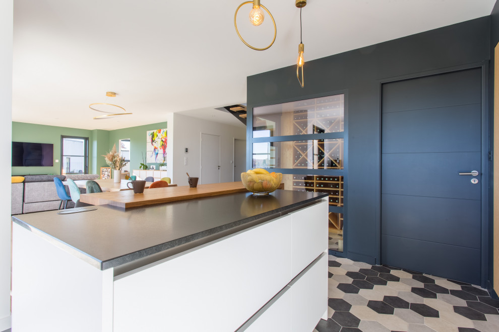 Inspiration for a large modern l-shaped open plan kitchen in Rennes with an integrated sink, beaded inset cabinets, white cabinets, granite benchtops, black splashback, granite splashback, stainless steel appliances, cement tiles, with island, grey floor and black benchtop.