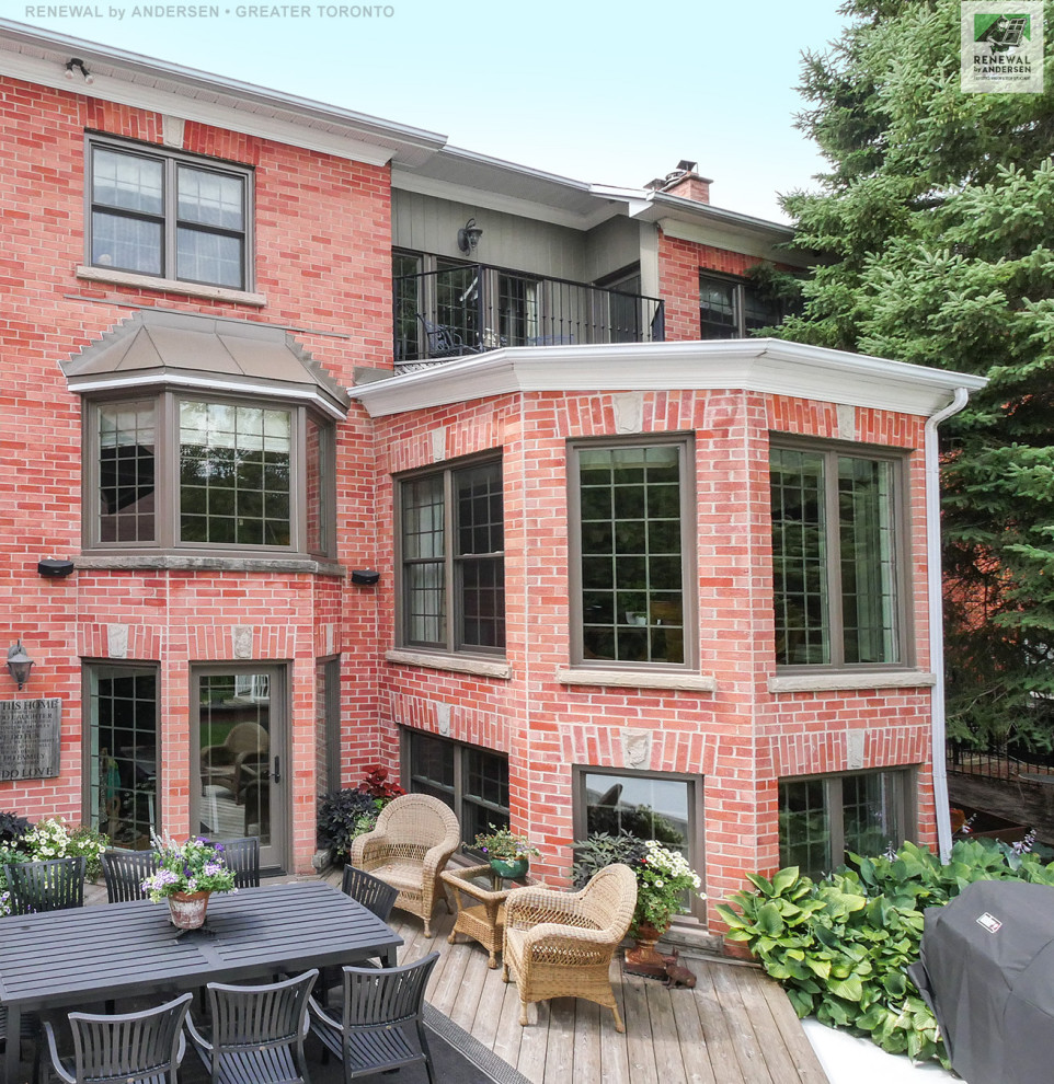 Large three-storey brick red house exterior in Toronto with a brown roof.