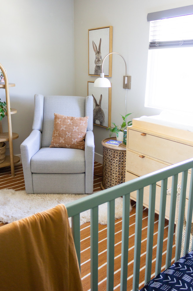 Imagen de habitación de bebé neutra contemporánea pequeña con paredes blancas, moqueta y suelo naranja