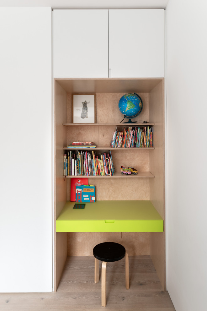 This is an example of a contemporary gender-neutral kids' study room for kids 4-10 years old in London with white walls, light hardwood floors and beige floor.