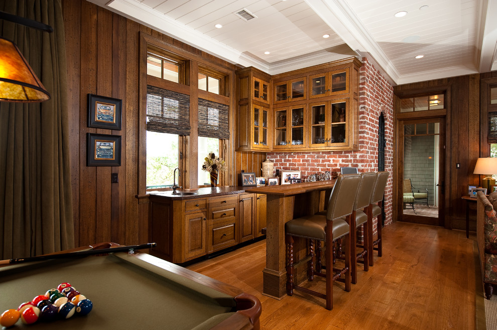This is an example of a country galley seated home bar in Charleston with an undermount sink, raised-panel cabinets, medium wood cabinets and medium hardwood floors.