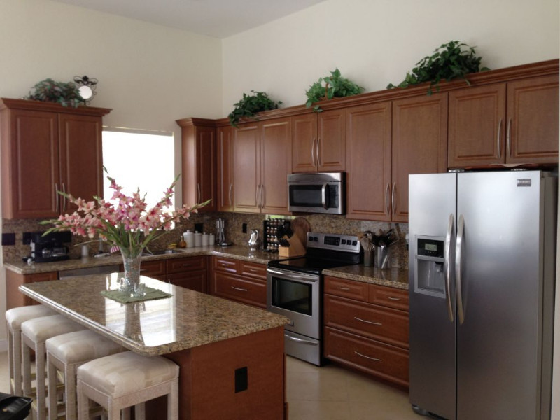 Inspiration for a l-shaped porcelain tile eat-in kitchen remodel in Miami with a double-bowl sink, beaded inset cabinets, medium tone wood cabinets, granite countertops, multicolored backsplash, stainless steel appliances and an island