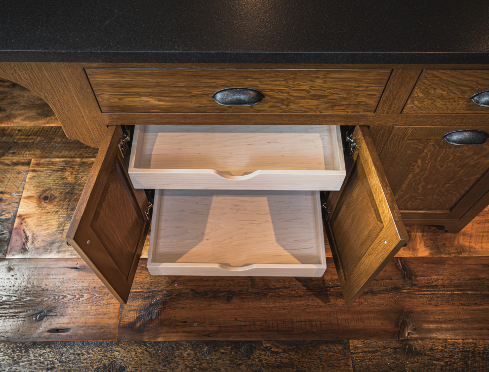 Inspiration for a rustic medium tone wood floor and exposed beam kitchen remodel with an undermount sink, shaker cabinets, granite countertops, black backsplash, granite backsplash, stainless steel appliances, an island and black countertops