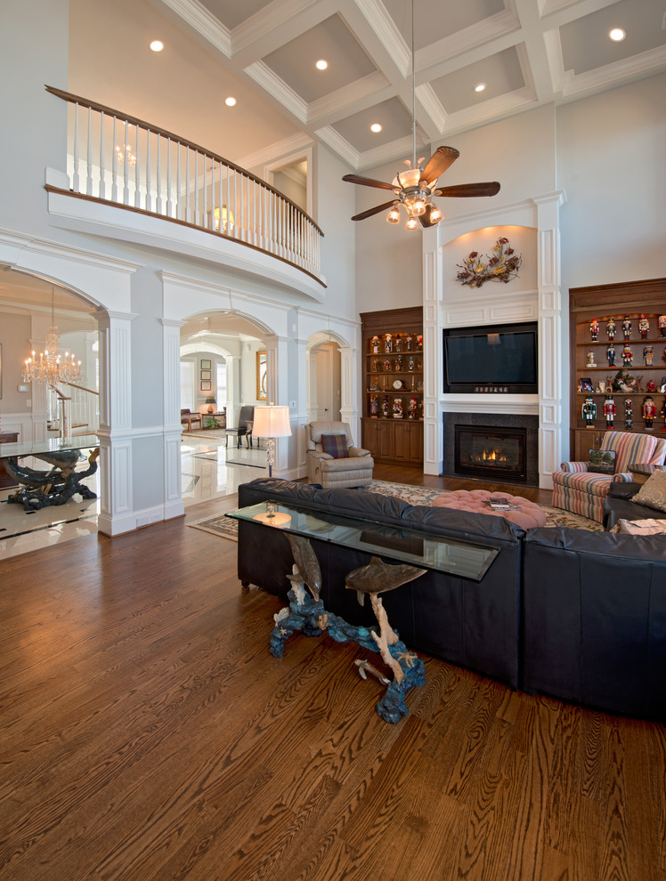 This is an example of a large traditional open concept family room in Other with a library, grey walls, a standard fireplace, a tile fireplace surround, a built-in media wall, dark hardwood floors and brown floor.