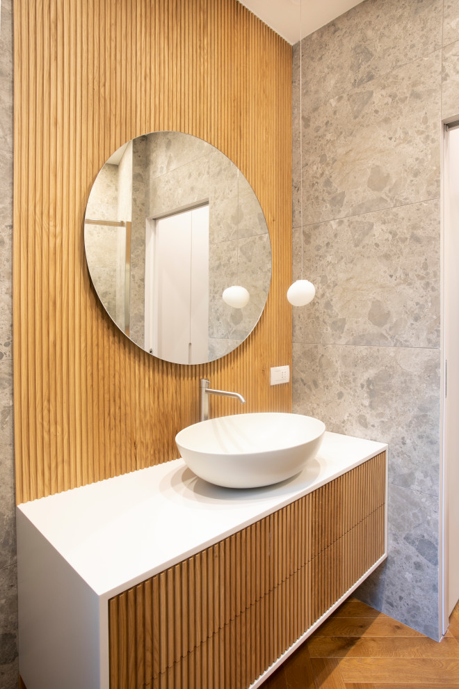 Mid-sized modern 3/4 bathroom in Milan with grey cabinets, an alcove shower, gray tile, porcelain tile, dark hardwood floors, solid surface benchtops, brown floor, a sliding shower screen, white benchtops, a single vanity, a floating vanity and recessed.