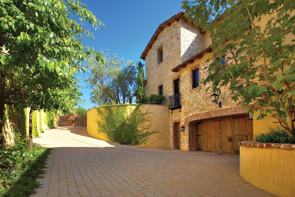 Inspiration for a large mediterranean three-storey yellow exterior in Orange County with stone veneer and a gable roof.