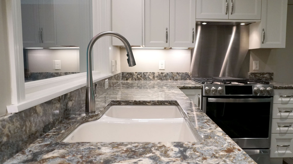 Example of a minimalist u-shaped porcelain tile and brown floor eat-in kitchen design with an undermount sink, shaker cabinets, white cabinets, quartz countertops, stainless steel appliances, a peninsula and multicolored countertops