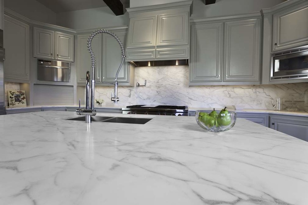 Example of a large transitional l-shaped brown floor and dark wood floor enclosed kitchen design in Baltimore with marble backsplash, paneled appliances, an island, a farmhouse sink, recessed-panel cabinets, white cabinets, marble countertops and gray backsplash