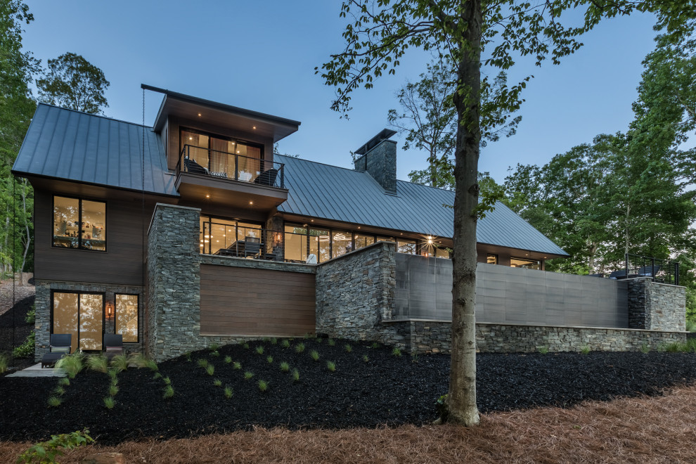 Ejemplo de fachada de casa marrón y negra contemporánea de tamaño medio de tres plantas con revestimiento de madera, tejado a dos aguas, tejado de metal y tablilla