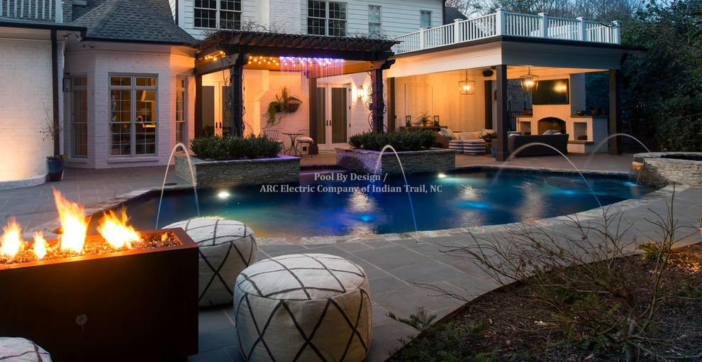Example of a huge backyard tile and custom-shaped hot tub design in Charlotte