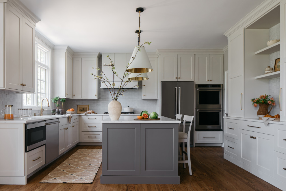 Mid-sized transitional galley medium tone wood floor and brown floor eat-in kitchen photo in Chicago with a double-bowl sink, recessed-panel cabinets, white cabinets, quartzite countertops, white backsplash, mosaic tile backsplash, stainless steel appliances, an island and white countertops